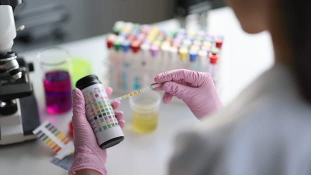 Close-up of laboratory assistant making medical test using testing strip. Woman holding ph-test in hands. Medicine and healthcare concept