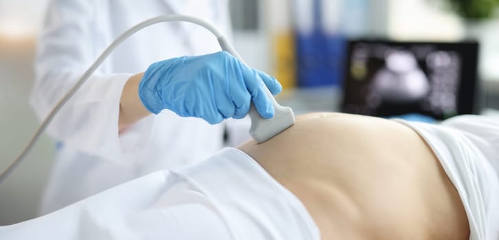 Close-up of gynecologist doing ultrasound scan on belly, pregnancy screening. Female patient examining baby health. Medicine and gynecology concept