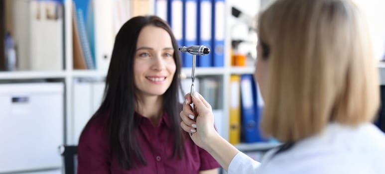 Portrait of neurologist doctor driving hammer tool in front of patient eyes in clinic. Medical checkup, health diagnostics and doctor appointment concept