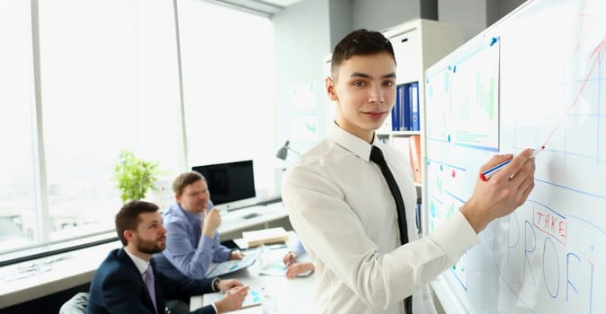 Portrait of smart man making presentation of profits for colleagues. Manager showing finance statistics to team. Business training, seminar or brainstorming concept