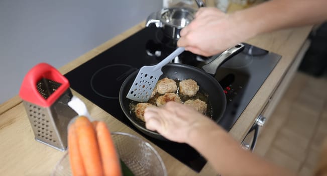 Top view of man frying meat balls in pan on kitchen stove. Freshly prepared food. Food blogging or vlogging, making content