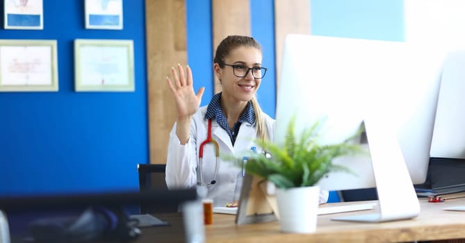 Portrait of female practitioner greeting patient via video call. Physician speaking with patient remotely. Doctor online and distance medicine concept