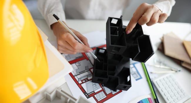 Top view of female architect working at new house project. Woman comparing plan and building layout. Architecture, building and creation of modern projects