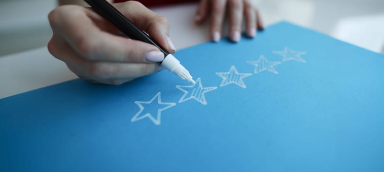Close-up hand drawing five stars rating on chalkboard. User experience, customer testimonials, vote and feedback or service assessment concept