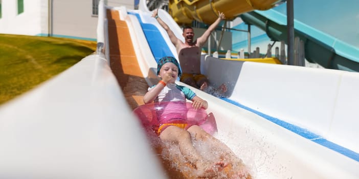 Portrait of little kid girl sliding down on water slide. Child having fun in aqua park. Leisure time and entertainment concept