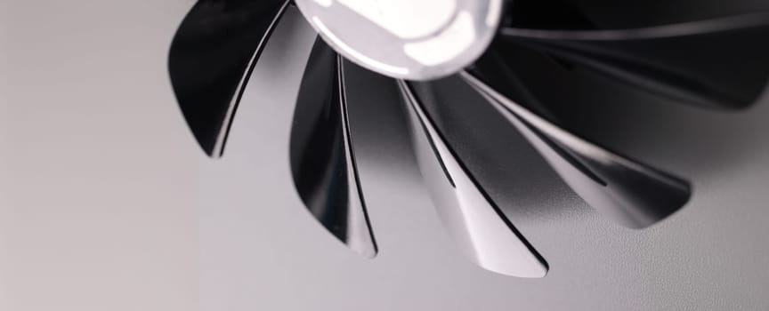 Close-up of cooling fan with black plastic blades on grey background. Car details parts. Device for cooling or ventilation