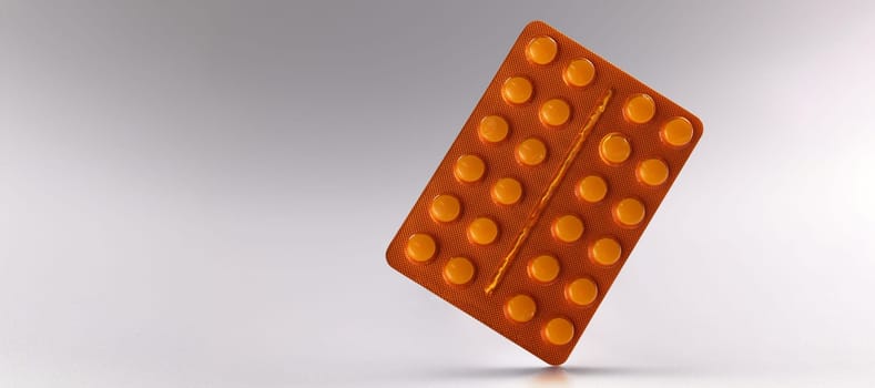Close-up of blister with tablets, daily dose of medication for person. Pills in orange package. Prescription, recovery, medicine and healthcare concept