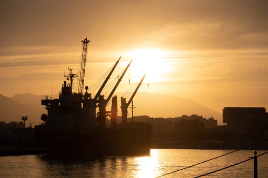 Sundown Cargo Ship Silhouette at Harbor With Faint Mountainous Backdrop
