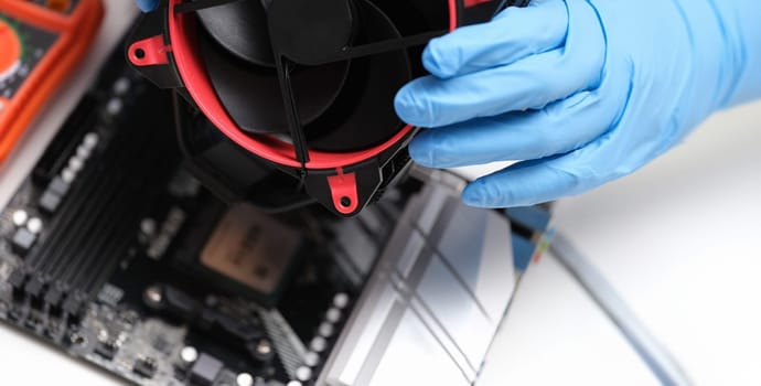 Close-up of man in white gloves installing laptop fan. Tech installing cooling fan. Laptop disassembling parts and devices concept