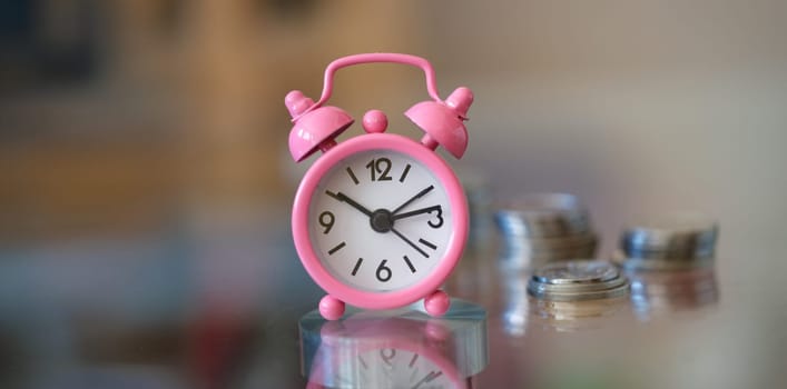 Close-up of alarm clock and money coin stack on table. Finance sustainable development, economic growth. Banking and business idea. Time for savings money concept