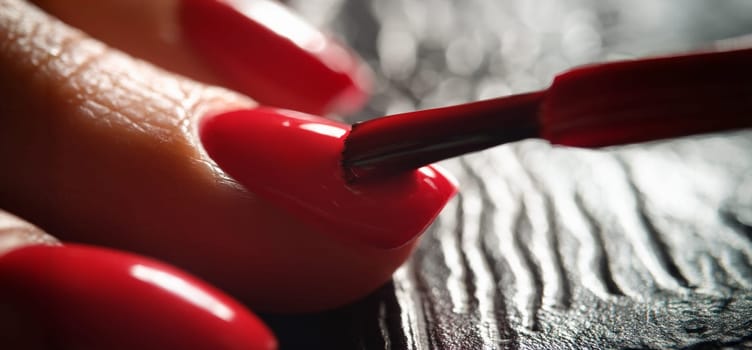 Master painting nails with bright red varnish to client closeup. Quality service in beauty industry professional manicure concept