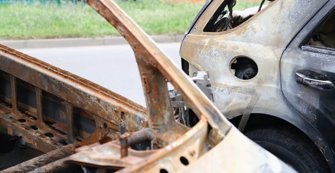 Close-up of iron parts of burnt vehicle, cars after accident. Riot, civil protest, hooliganism or criminal in city concept