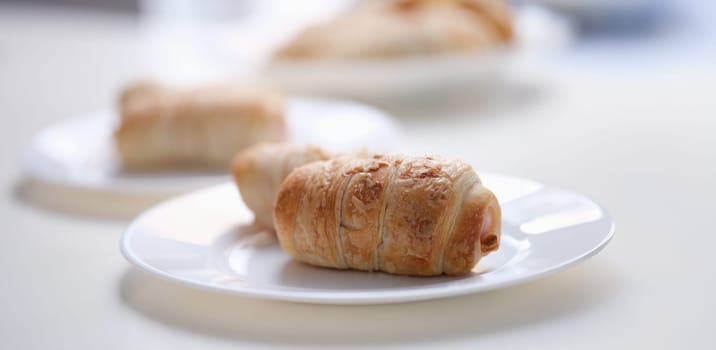Close-up of homemade sausages in dough on white plate. Freshly baked sausage rolls. Lunch and yummy snack concept