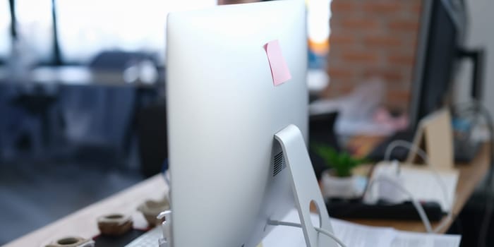 Close-up of computer monitor with sticker on it in office. Modern pc display with paper note, copy space. Digital device