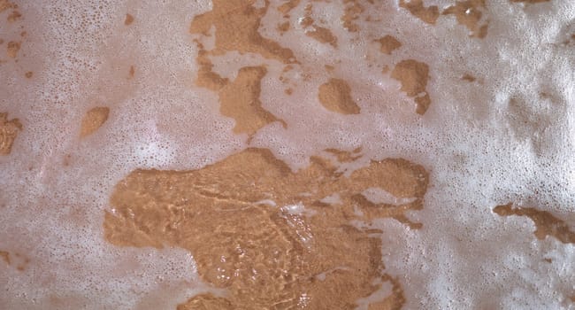 Top view of soft ocean or sea wave with foam on sandy beach. Summer sea vacation and leisure at sea concept, empty copy space