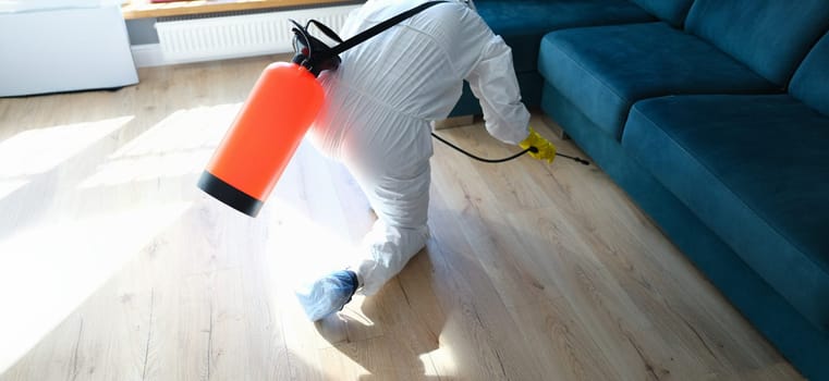 Close-up of man in hazmats making disinfection in flat. Professional cleaning with disinfectant spray. Coronavirus disinfection concept