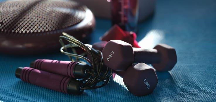 Close-up of dump rope and dumbbells, athletes set for workout. Fitness, sport activity and healthy lifestyle, weight loss concept