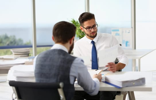 Portrait of coworkers men working at financial papers, solve and discuss problems. Businessmen analysing project profitability. Investment market concept