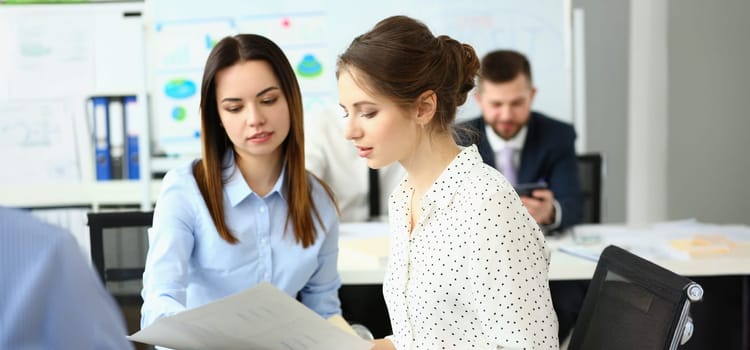 Portrait of businesswomen working together at company office, teamwork and teambuilding. Colleagues discussing details of project development