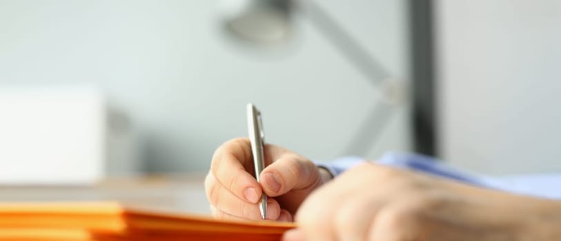 Close-up of male hand writing personal address on yellow envelope. Signing envelopes and correspondence processing. Delivery service concept
