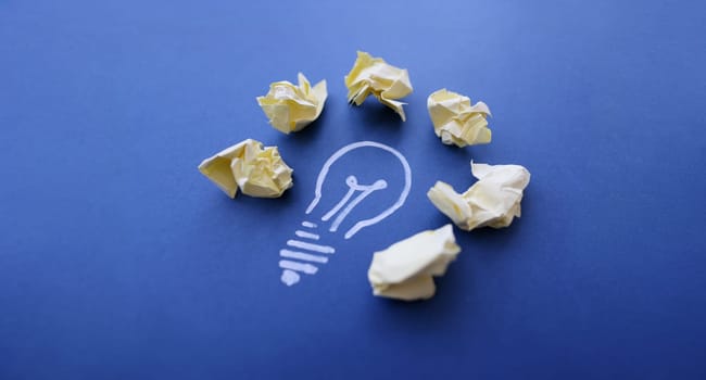 Close-up of chalk lightbulb with crumpled papers, creativity and inspiration. Creation new idea, brainstorming, innovation and business concept