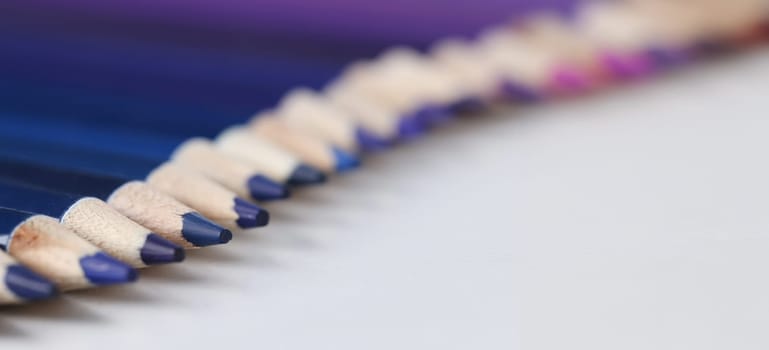 Close-up of set of blue identical pencils lie in raw. Several sharpened pencils of blue color
