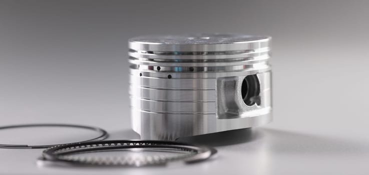 Close-up of forcer and piston rings, internal combustion engine on grey background. Car details, transport, component concept