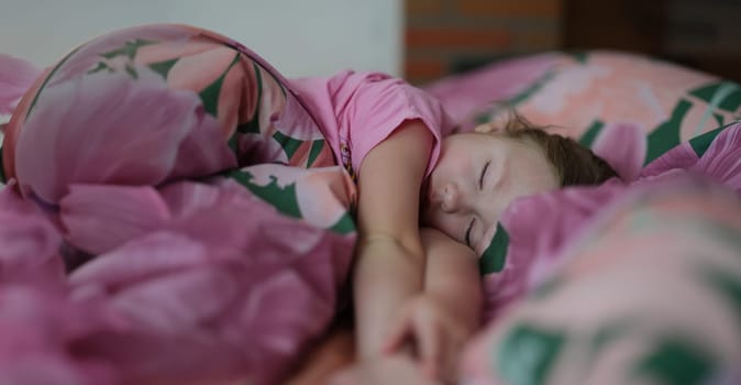Portrait of little girl kid sleeping sweetly in bed. Daytime sleep. Small child resting after active day. Healthy lifestyle concept