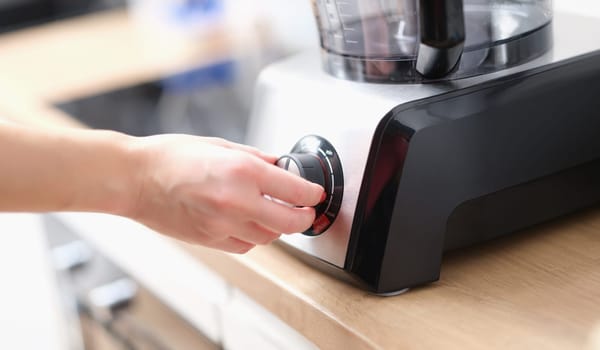 Close-up woman using blender to make tasty dish. Female hand touching speed controller. Cooking food concept