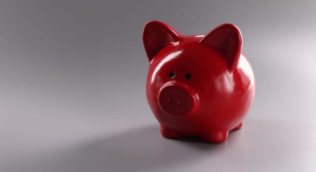 Close-up of red piggy bank on grey background, saving money. Finances, savings, success, and retirement concept