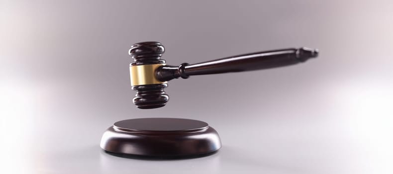 Close-up of wooden judges gavel on soundboard on grey background. Attorney tool for legal service. Court, law, verdict, legality and justice concept