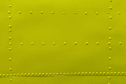 Abstract background made of sheet metal with rivets, yellow background.