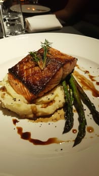 A classic seared salmon fillet with a golden crust, presented over a creamy pure and garnished with green asparagus, captures the essence of gourmet simplicity