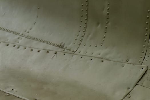 The side of the aircraft is painted green with rivets. Aircraft surface. Armor of military equipment.