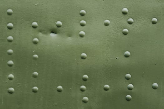 The surface of an old damaged aircraft skin with rivets.