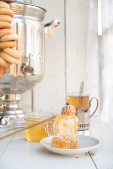 honeycomb with honey on a saucer and tea from a Russian samovar with bagels, Slavic tea party, high quality photo