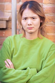 Attractive confident chinese teenage student looking at camera outdoors. Boy standing with angry face.
