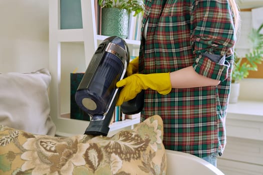 Young woman doing vacuuming, vacuuming pillows on couch. Cleanliness, cleaning, hygiene, youth concept