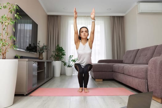 fitness woman doing deep squats workout standing on floor mat at home
