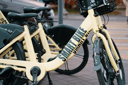 A yellow smart bicycle with a black bicycle wheel rim is parked next to a regular black bicycle