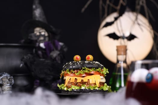 Monster Burger. Black bun, juicy beef cutlet, lettuce, onion, tomato and cheese in the shape of teeth, eyes with olives. Definitely a pick-me-up and a perfect Halloween party appetizer.