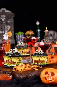 Monster Burger. Black bun, juicy beef cutlet, lettuce, onion, tomato and cheese in the shape of teeth, mozzarella eyes with olives. Definitely a pick-me-up and a perfect Halloween party appetizer.