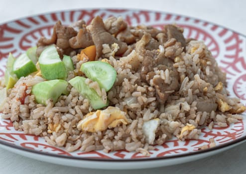 Traditional Egg fried rice with Fried pork, Tomato, Onion and Sliced ​​cucumber. Asian food style, Space for text, Selective focus.
