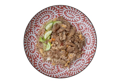 Traditional Egg fried rice with Fried pork, Tomato, Onion and Sliced ​​cucumber on ceramic plate isolated on white background with clipping path. Asian food style, Top view, Selective focus.