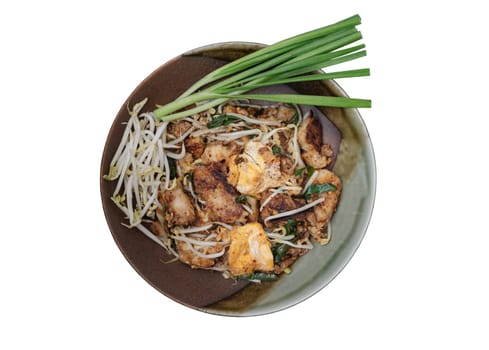 Stir-fried soft turnip cake or Fried radish cake (chai tow kway) with bean sprout and chives on ceramic plate isolated on white background with clipping path. Thai - Chinese food called Kanom Pak kad or Char Koay Kak, Top view, Selective focus.