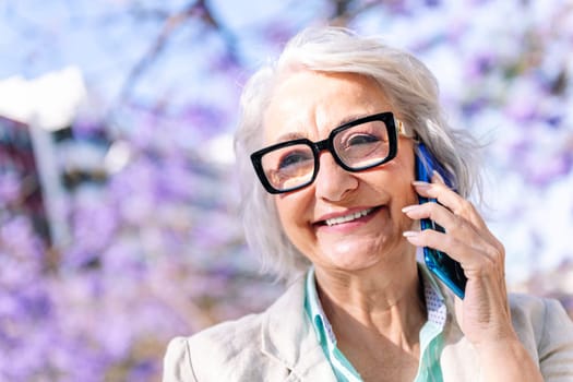 portrait of a lively mature woman smiling happy while talking on mobile phone, concept of technology of communication and modern lifestyle in adulthood, copyspace for text