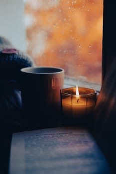 A burning candle on the window is autumn . the comfort of home . autumn comfort . autumn mood. The chondra .