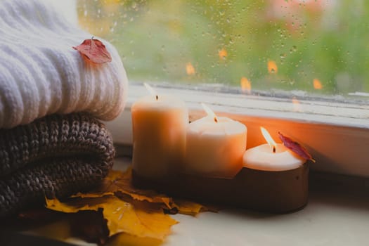 A burning candle on the window is autumn . the comfort of home . autumn comfort . autumn mood. The chondra .