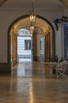 Munich, Germany - Dec 21, 2023 - Perspective view of Arches corridor with Antique lantern hanging from ceiling in Ancient building. Design elements of European architecture structure, Space for text, Selective focus.