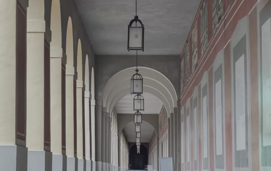 Munich, Germany - Dec 22, 2023 - Perspective view of Long corridor with Antique lantern hanging from ceiling and Beautiful columns inside Hofgartenarkaden (Munchen). Design elements of European architecture structure, Space for text, Selective focus.